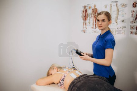 An older woman in a rehabilitation center undergoing an electromyostimulation procedure