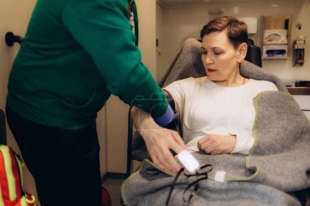 Un médecin prend la pression artérielle d'une femme âgée dans une ambulance