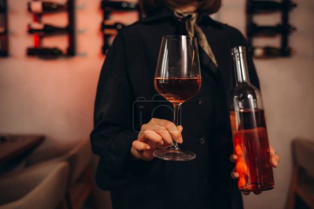 Sommelier femenino remolino de vino tinto en vidrio sobre fondo de bodega que se encuentra en la bodega. Examen de experto en vino para estudiar diferentes vinos. 