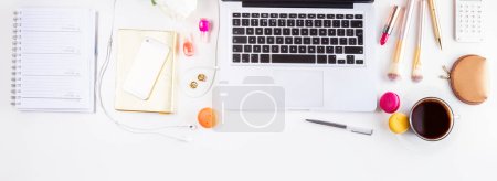 Photo for Feminine workspace border with notebook, laptop, phone, coffee and flowers, top view and copy space on empty screen - Royalty Free Image