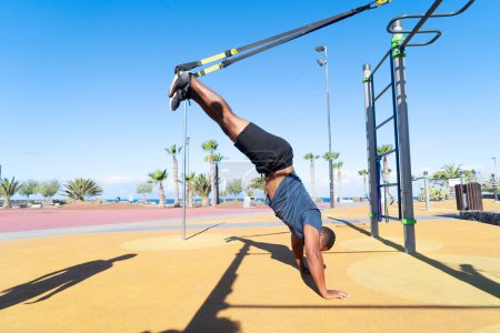 Photo for Suspension sport training - athletic man training with trx belt on the outdoor sports ground - Royalty Free Image