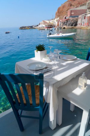 Téléchargez les photos : Chaise en bois relaxante et table à manger avec vue sur la caldera, Santorin, Grèce - en image libre de droit