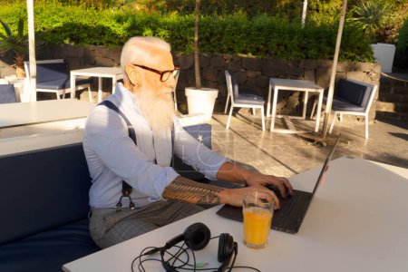 Photo for Senior man working with laptop on cafe or home terrace - Royalty Free Image