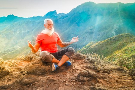 Téléchargez les photos : Homme athlète senior saluant le lever du soleil et la méditation, la vie consciente et le concept de bien-être sain - en image libre de droit