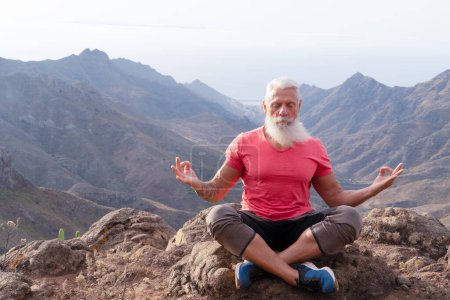 Téléchargez les photos : Homme athlète senior saluant le lever du soleil et la méditation, la vie consciente et le concept de bien-être sain - en image libre de droit