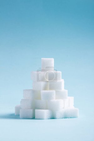 Foto de Montón de terrones de azúcar sobre fondo azul - Imagen libre de derechos
