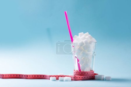 Foto de Cubos de azúcar en vidrio con cinta métrica, diabetes y concepto de uso excesivo de azúcar, fondo azul con espacio para copiar - Imagen libre de derechos