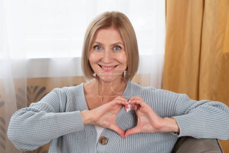 Blonde Seniorin entspannt, Frau mit Herz aus Händen, glücklicher Ruhestand und Charity-Konzept