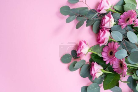 fondo del día de la boda o de las madres, ramo de rosas y herberas con hojas de eucalipto frescas sobre fondo rosa liso, espacio de copia