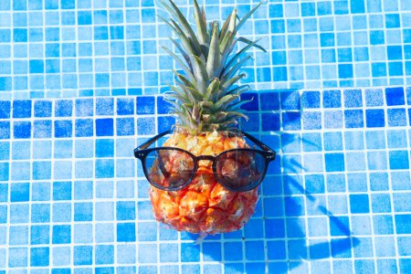 pinapple with sunglasses sunbathing in swimming pool