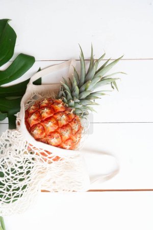 pinapple on white wooden table in bag