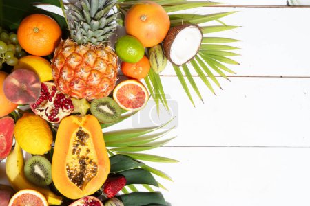 Summer mix of tropical fruits over white wooden background with copy space