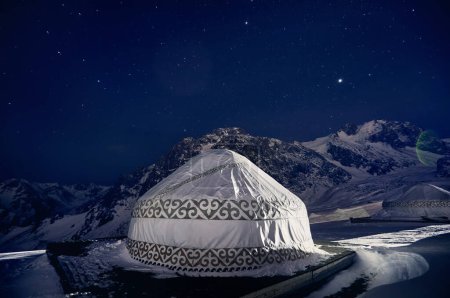 Jurte oder Jurte Nomadenhaus im Skigebiet Shymbulak in Almaty, Kasachstan. Winternacht-Astrofotografie mit Sternen gegen Berggipfel