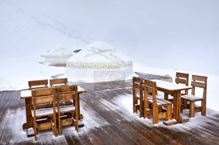 Téléchargez les photos : Hotel and Restaurant from Yurt nomadic house complex and table with chair at Station de ski Shymbulak in Almaty, Kazakhstan. Concept de tourisme de plein air en hiver. - en image libre de droit
