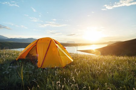 Photo for Yellow tourist tent camping in the mountains near lake at sunset Kazakhstan. Outdoor vacation nature concept. - Royalty Free Image