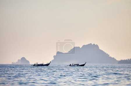 Foto de Barcos de cola larga tradicionales en silueta cerca de islas tropicales al atardecer en el Mar de Andamán, sur de Tailandia - Imagen libre de derechos
