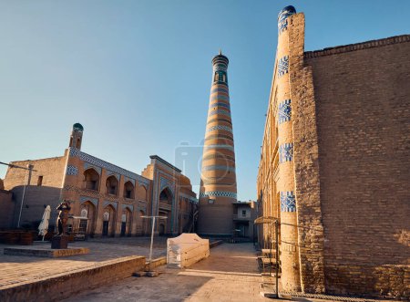 Photo for Public square with statue of flutist and Minaret in Ichan Kala of Khiva in Uzbekista - Royalty Free Image