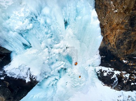 Aerial drone view of athlete Ice climbing big frozen waterfall in Barskoon gorge the mountain valley in south part of Issyk Kul lake, Kyrgyzstan
