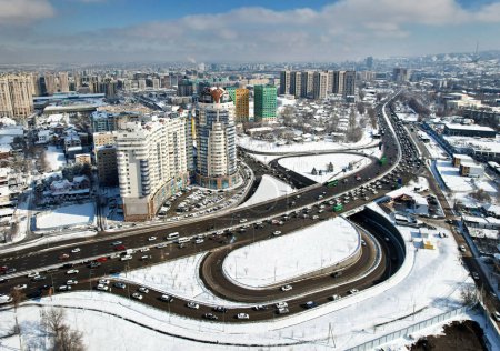 Vista aérea del dron panorámica de la avenida Alfarabi con el tráfico de coches y grandes edificios rascacielos en invierno en la ciudad de Almaty, Kazajstán