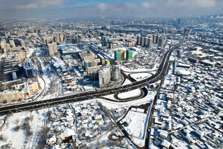 Vista aérea del dron panorámica de la avenida Alfarabi con el tráfico de coches y grandes edificios rascacielos en invierno en la ciudad de Almaty, Kazajstán