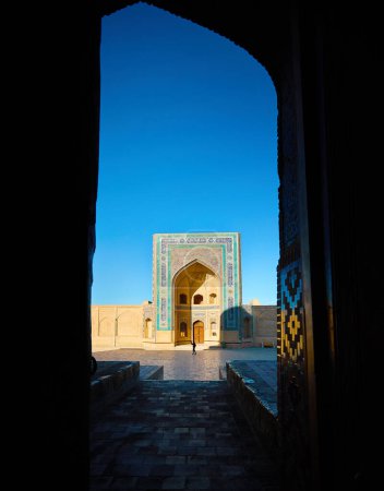 Schöne Ansicht von Wahrzeichen außen Madrasah von Abdulaziz Khan und Touristen gerahmten Bogen Tor in der Altstadt von Bokhara, Usbekistan