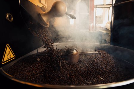 Téléchargez les photos : Grains de café chauds versant dans un plateau de refroidissement en métal, puis rôtissant et mélangeant par pelle rotative - en image libre de droit