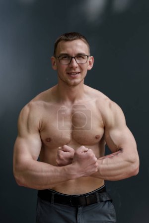 Photo for A muscular man with eyeglasses confidently flexes, a symbol of brain and brawn - Royalty Free Image