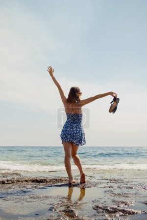 Eine Frau tanzt frei am Strand, ihr Kleid und ihre Haare werden von der belebenden Meeresbrise aufgewirbelt