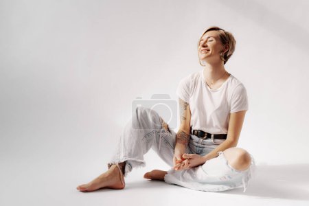 Eine junge Frau in entspannter Pose, mit weißem T-Shirt und leichter Jeans, sonnt sich in einem Moment sonnigen Glücks