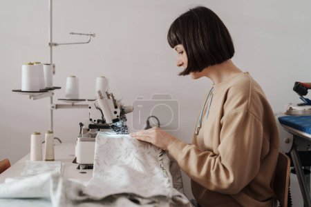 Photo for A woman in her mid-thirties is sewing diligently in her well-equipped workshop. - Royalty Free Image