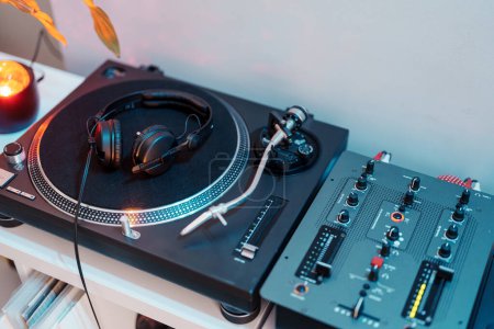 Close-up of a DJs turntable, headphones, and mixer ready for a music session.