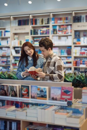 A young man and woman happily exploring books in a modern library.