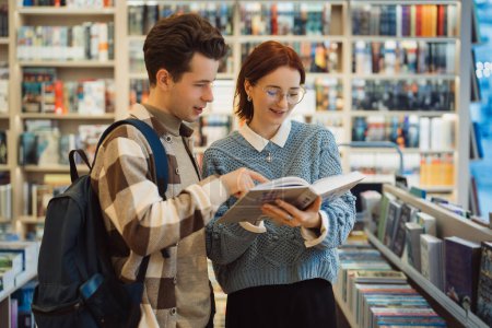 A young man and woman explore a selection of books in a cozy bookstore. They appear engaged and happy as they discuss their finds among shelves filled with books.