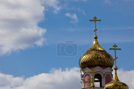 Iglesia cúpula con cruz en el cielo nublado soleado