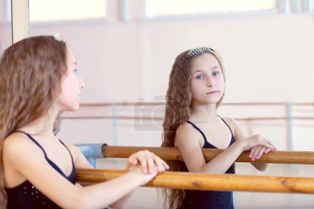 Téléchargez les photos : Image de jeune ballerine bouclée posant en regardant dans le miroir - en image libre de droit