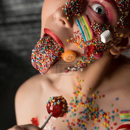 Téléchargez les photos : Fille avec des bonbons et du caramel sur son visage lécher chupa-chups coup - en image libre de droit