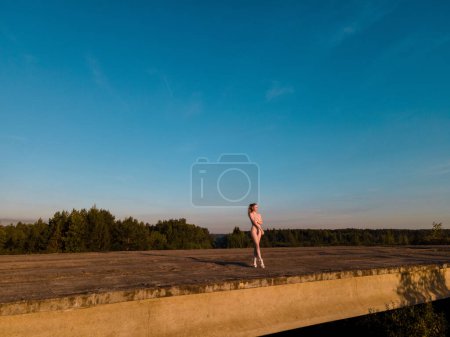 Téléchargez les photos : Femme rouge nue sexuelle éloignée debout sur un pont en béton et regarder le lever du soleil - en image libre de droit