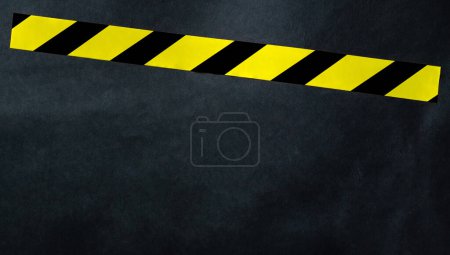 Photo for Yellow tape with black and yellow stripes on a dark background. Warning ribbon. - Royalty Free Image