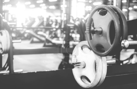 Téléchargez les photos : Rack avec des poids différents dans une salle de gym moderne, plan noir et blanc - en image libre de droit