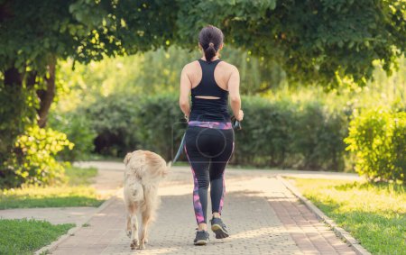 Foto de Deporte chica corriendo con golden retriever perro al aire libre. Joven mujer corriendo con perrito mascota en verano - Imagen libre de derechos