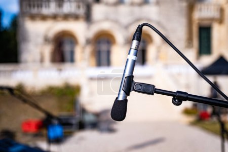 Téléchargez les photos : Microphone for outdoor music event festival with old building on background. Electronic speaker closeup for live perfomance at street - en image libre de droit