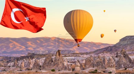 Foto de Bandera de Turquía contra globos aerostáticos que vuelan en el cielo al atardecer en Capadocia, Turquía - Imagen libre de derechos