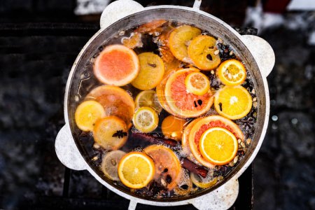 Téléchargez les photos : Vigne épicée cuite avec des oranges en pot dans le marché de la nourriture de rue. Boisson alcoolisée chaude colorée au festival de foire en plein air gros plan - en image libre de droit