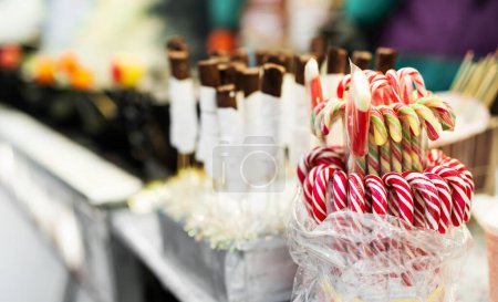 Photo for Traditional Christmas lollipop cane candies with red and white stripes at traditional street food festival market. Festive sweets at fair as symbol of Xmas - Royalty Free Image