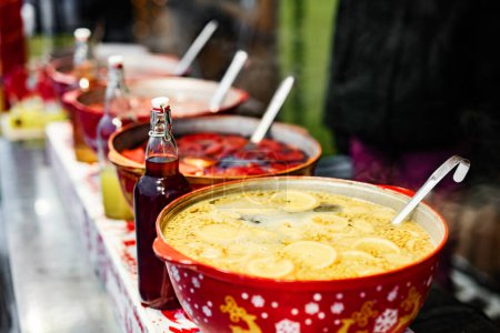 Photo for Beverages fruits and berries hot mulled wine in red pots in street food market. Colorful hot drinks at fair festival outdoors closeup - Royalty Free Image
