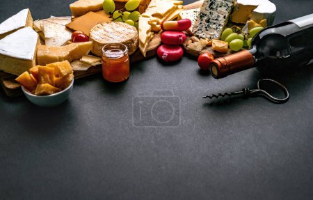 Foto de Diferentes tipos de queso servido con botella de vino para la nutrición gourmet. Set de parmesano y brie ecológico con delicatessen de alcohol de uva - Imagen libre de derechos