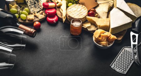 Foto de Diferentes tipos de queso servido con botella de vino, vasos y uva para la nutrición gourmet. Set de parmesano y brie ecológico con composición alcohólica - Imagen libre de derechos