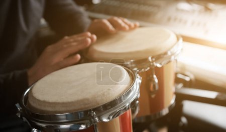 Téléchargez les photos : Musicien jouant de la main Bongo Drums à l'intérieur gros plan. Homme avec instrument de musique folklorique ethnique traditionnelle - en image libre de droit