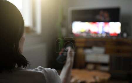 Téléchargez les photos : Woman watching television at home and eating chips - en image libre de droit