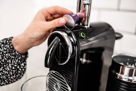 Photo for Girl hand put capsule to coffee machine at home kitchen closeup. Woman preparing italian caffeine beverage using professional espresso maker at home - Royalty Free Image